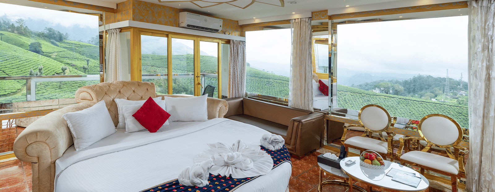 An interior view of the Jacuzzi 180-degree Suite at Parakkat Nature Hotel and Resorts, Munnar, featuring a large round bed, plush decorative pillows, and elaborate gold-toned ceiling accents.