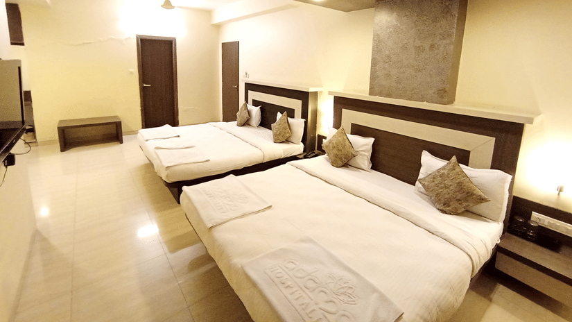 A family room  featuring two large double beds neatly made with white linens and decorative pillows.