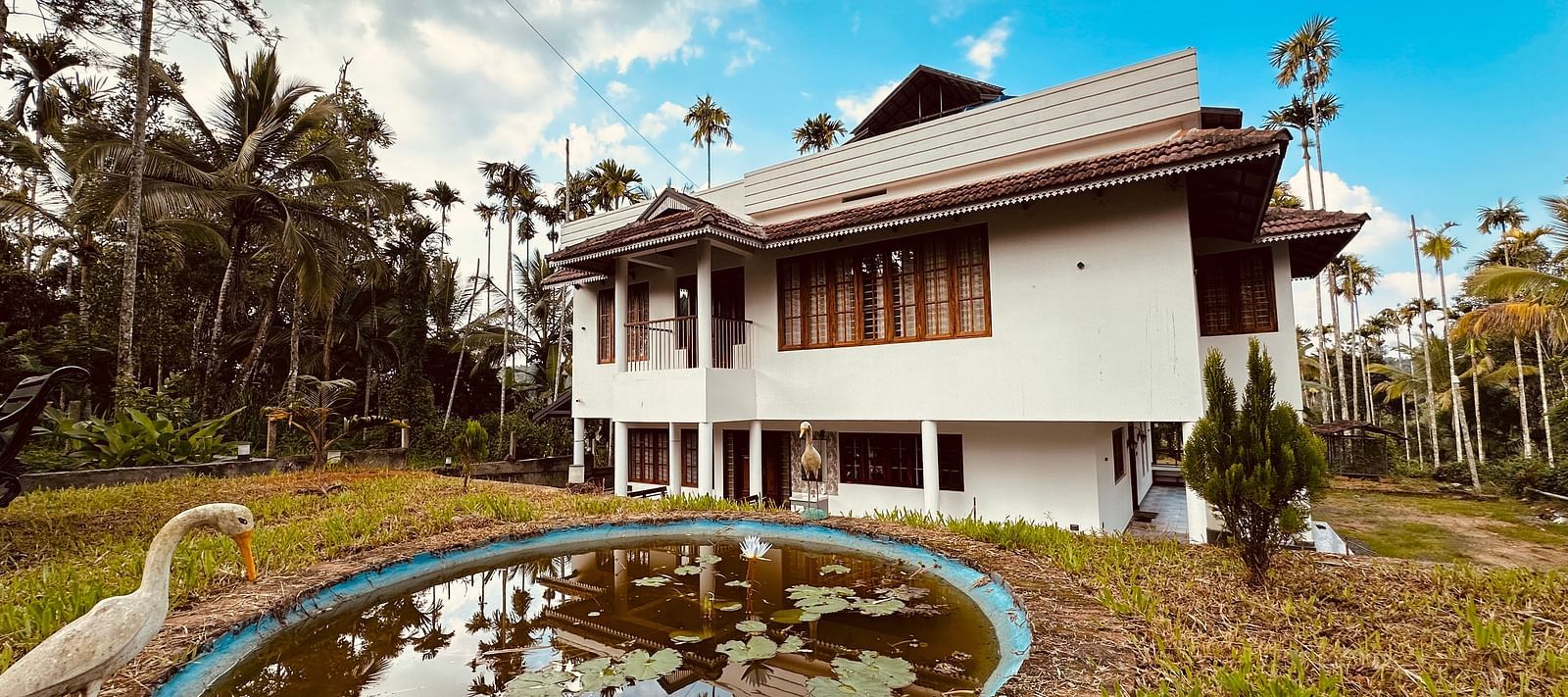 Image of the Facade of Ananda Holiday Home, Wayanad on a bright day wit a pond in front of it