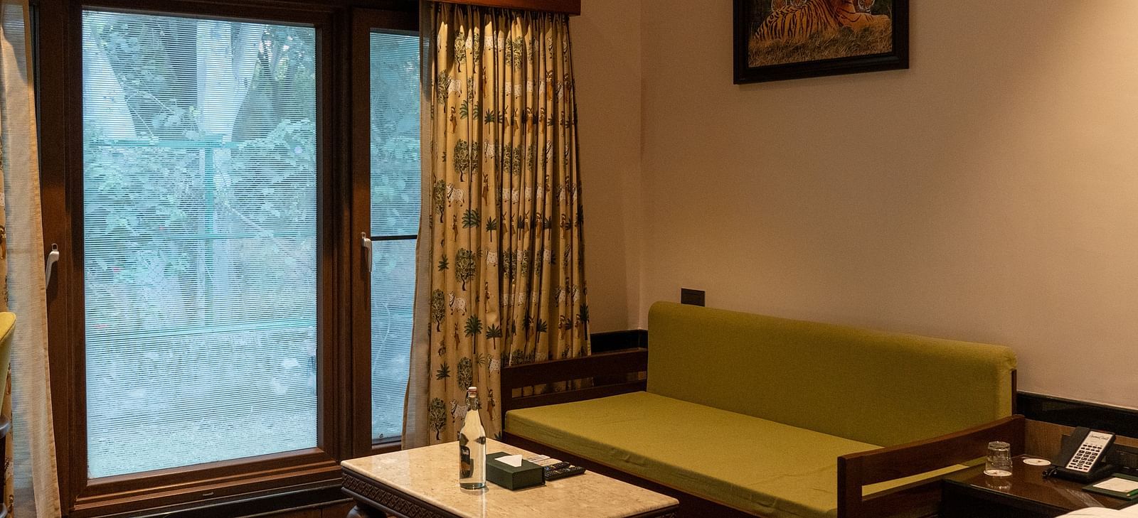 A comfortable living area in a guest room at Aamaghati Jungle Retreat Ranthambore with a sofa and coffee table.