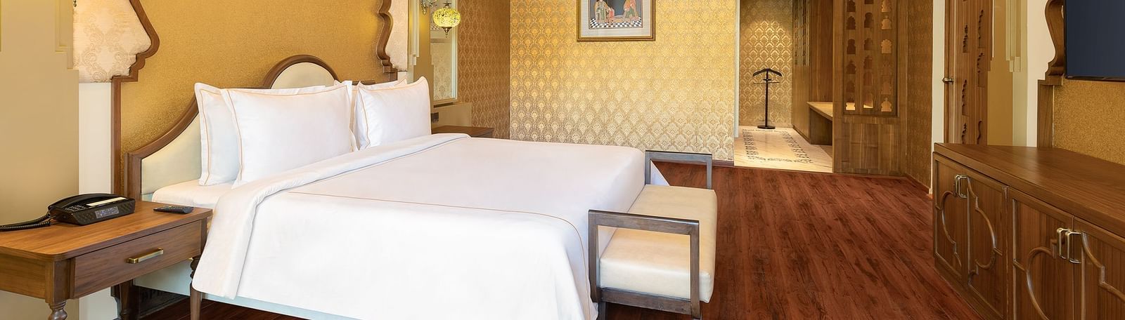 A spacious bedroom with clean white linen and ornate gold frames above the beds – Kaldan Samudra, one of the best luxury hotels in Mahabalipuram