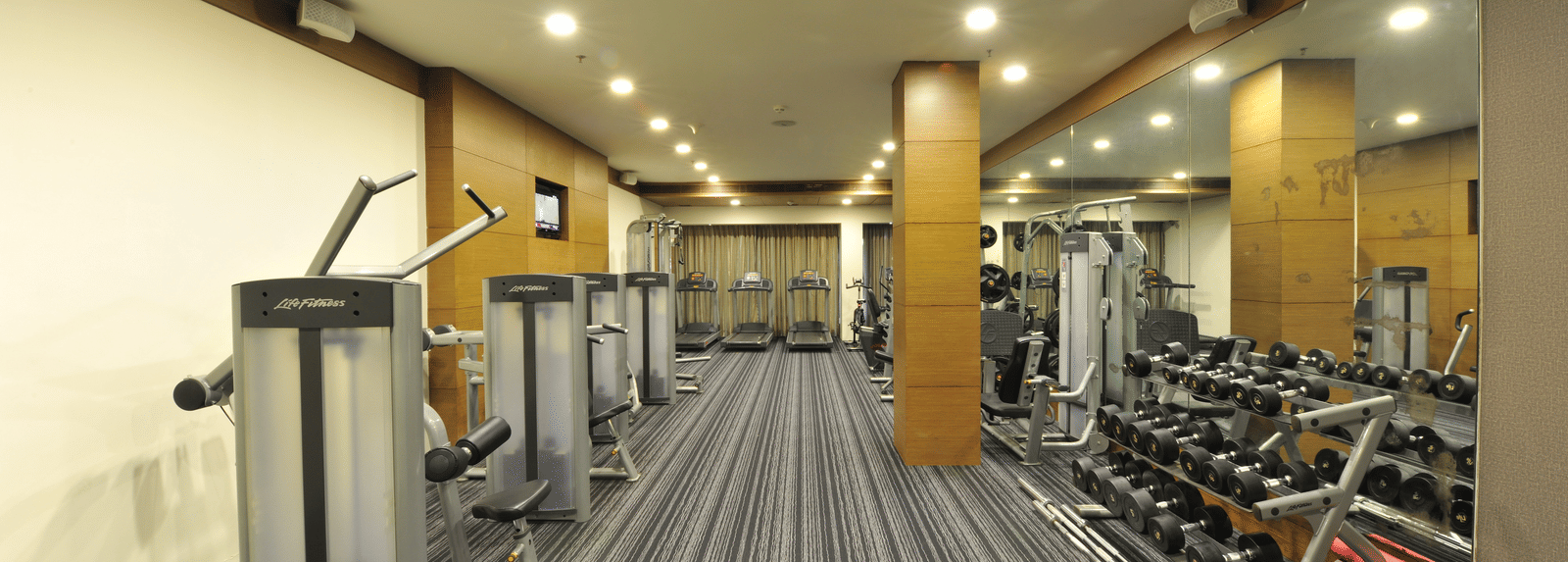 Modern gym with various workout machines and equipment at Narayani Heights Hotel & Resorts, Ahmedabad.