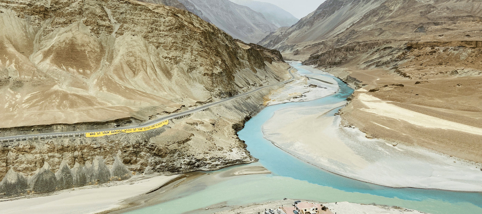 A high-angle view showing the confluence of 2 rivers winding through a vast mountain valley.