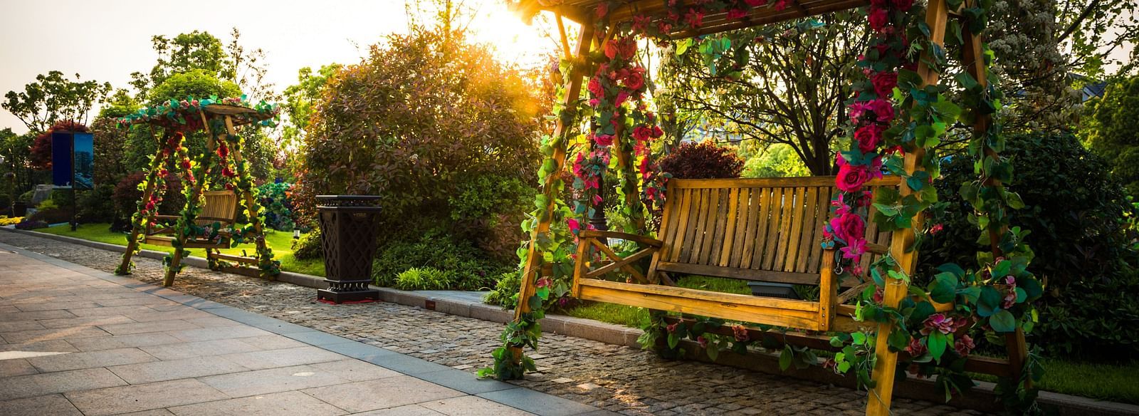 A wooden swing or bench in a garden setting and the sun casting a warm light and creating a lens flare effect. - Bamboo Saa Resort & Spa, Udaipur