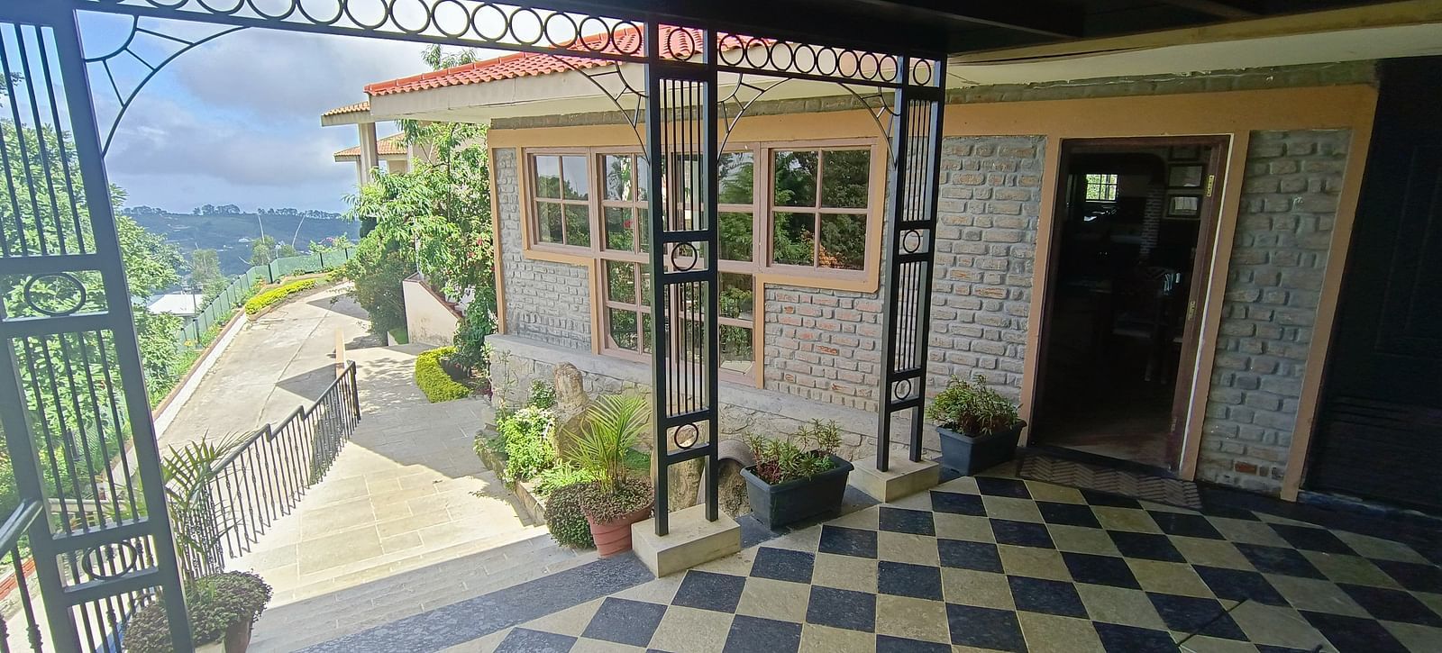 Exterior view of a restaurant with stone walls, surrounded by greenery and a paved path.