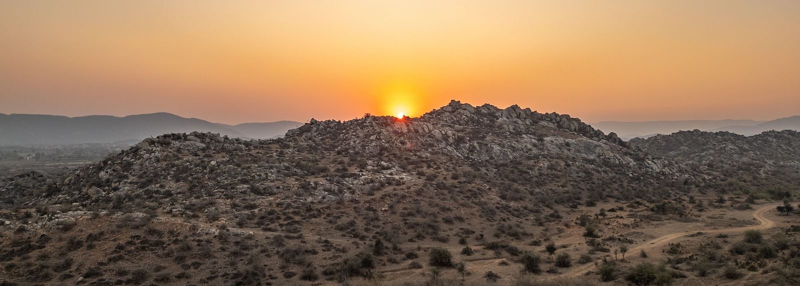 Image of sunrise taken from a far in a desert area
