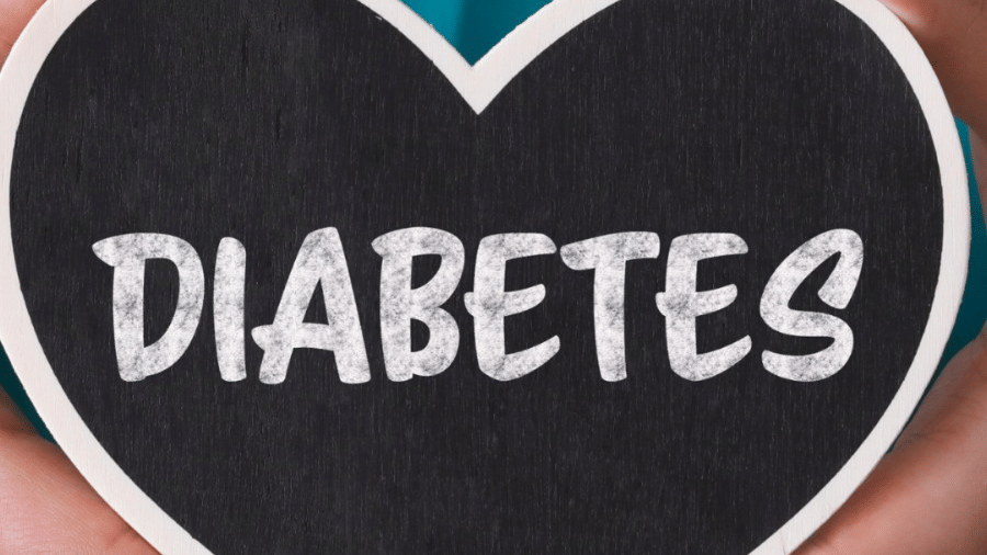 A person with a stethoscope holds a heart shaped object saying DIABETES