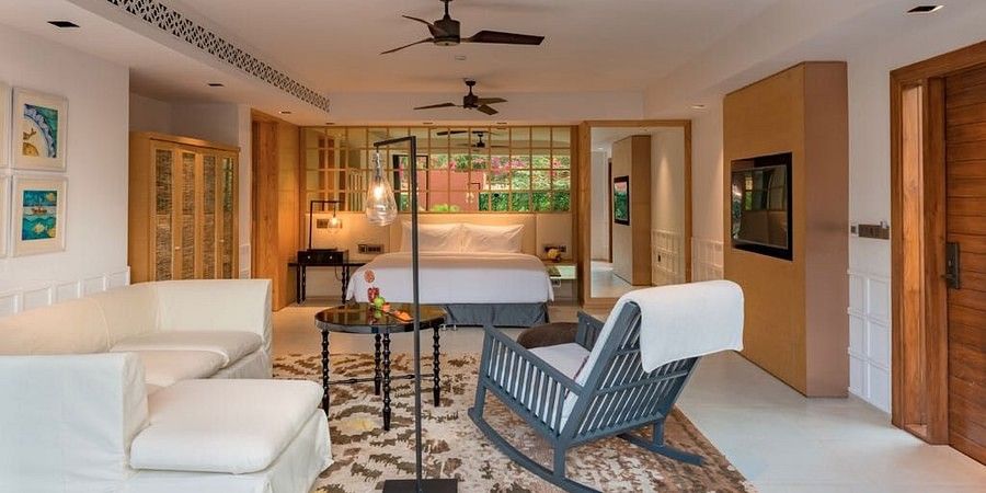 alt-text Room with a blue rocking chair and couches and bed with white covers