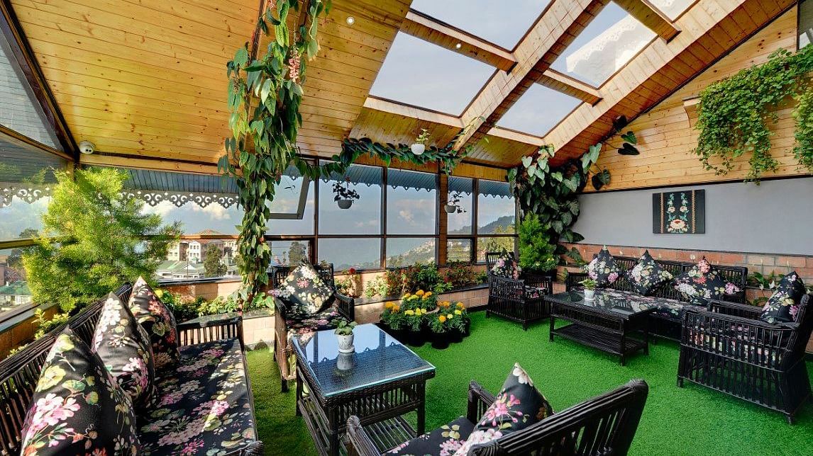 An image of the rooftop restaurant at Yashshree Mall Road, Darjeeling featuring decoration with plants and its seating arrangement