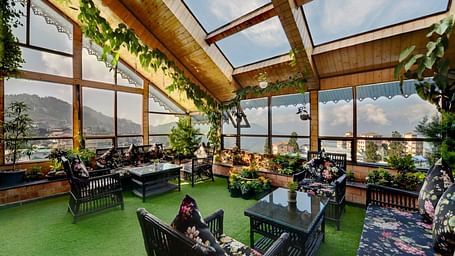 Image of the garden at Yashshree Mall Road, Darjeeling with seating area, glass roofs and walls.