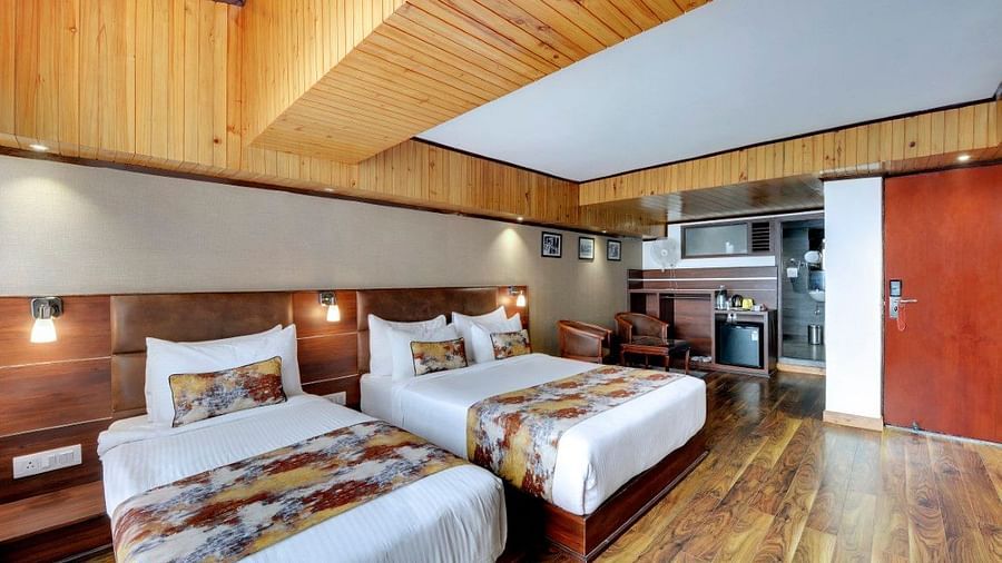 Image of Deluxe Triple Room with two beds, a seating area in the corner, a mini fridge at Yashshree Mall Road, Darjeeling.