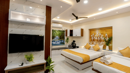 A hotel bedroom featuring twin beds with yellow runners, a wall-mounted TV, and wall decor | Hotel Aurora Bliss, Gachibowli
