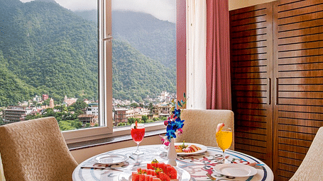 A beautifully set dining table in the suite served with fruits and juice at Regenta Inn DLS.