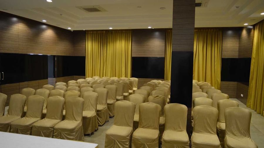A large banquet hall at The Royal Comfort, set up for a conference or event with rows of chairs facing a stage with a podium, all under warm lighting.