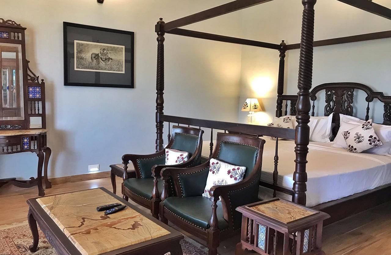 A traditional hotel bedroom with a four-poster bed and a sitting area - Khas Bagh, Jaipur.