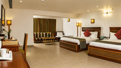 Family Room with twin beds, a cozy seating area, and warm lighting at Chariot Beach Resort, offering ample space for families to relax.