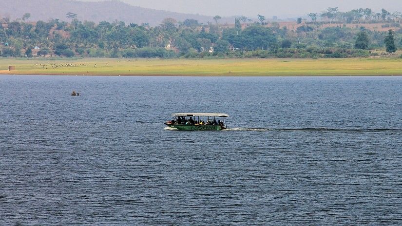A boat travelling in the kabini river with with trees in the background