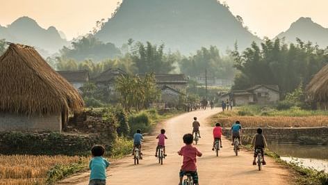 Kids riding their bicycles on a country road with mountains in the backdrop - WoCAL Retreat Ke Ga