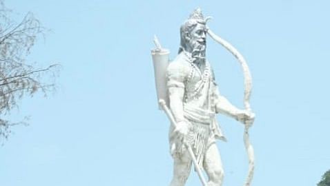 A white statue of Lord Parshuram standing on a podium with a sea on the background.