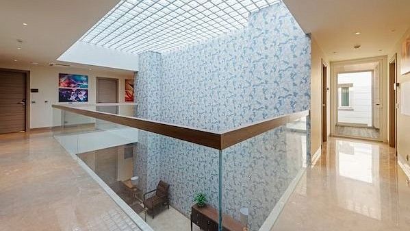 Upper-level hotel atrium with a glass ceiling, patterned blue feature wall, glass railings, and polished floors at Hotel Saket 27, New Delhi