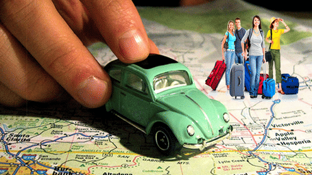 A hand moving a small green toy car on a map with miniature figures of people holding luggage standing beside it.