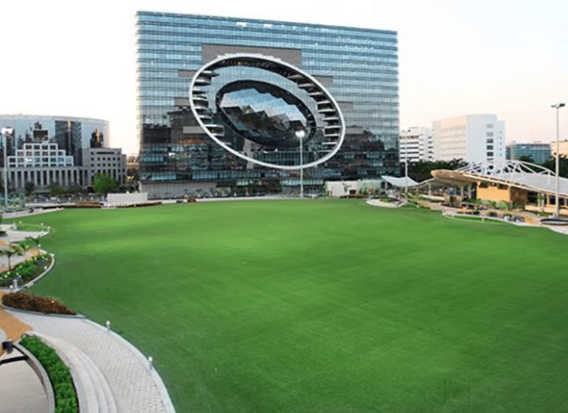 Lush green lawn of Jio World Garden in Mumbai, a popular event venue with a striking modern building in the background. 