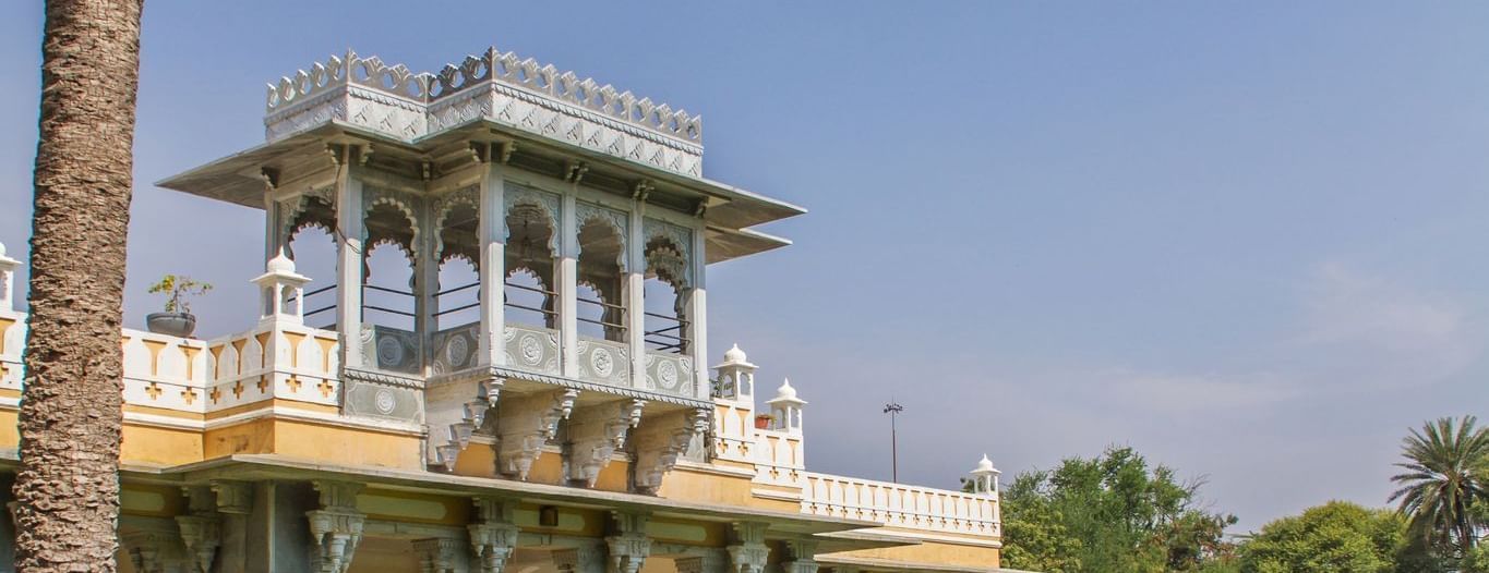 facade image of Dev Shree, deogarh featuring a vast levelled green lawn in the foreground during the day