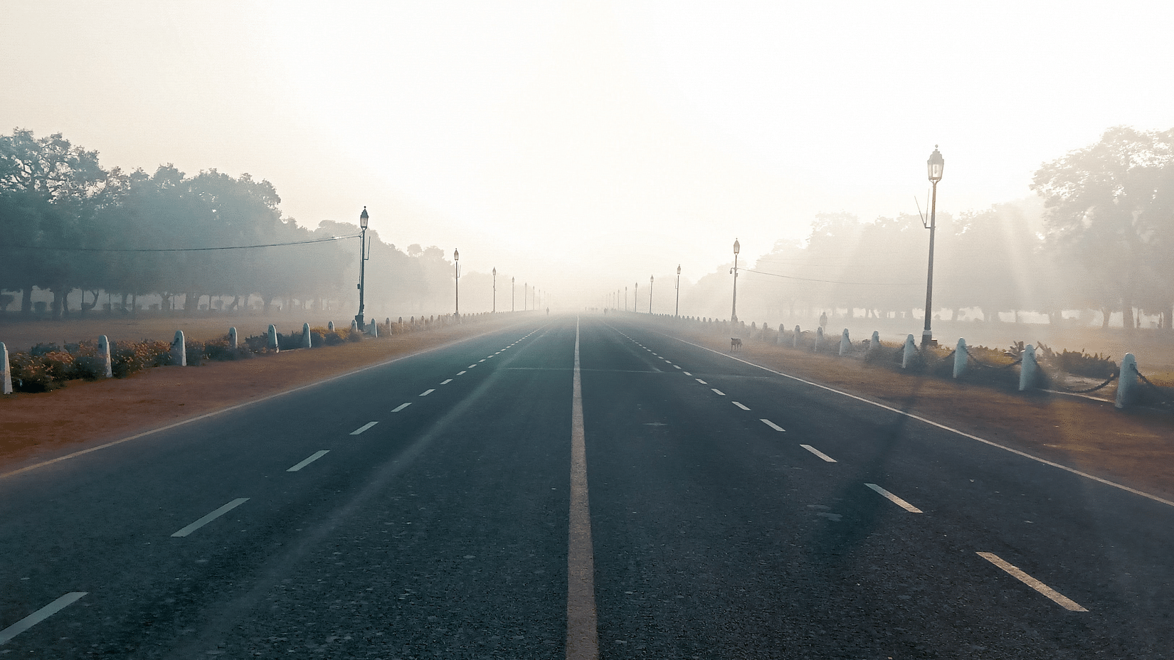 A road leading the india gate with mist cover in the background