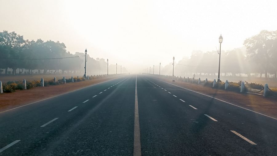 a road leading the india gate with mist cover in the background
