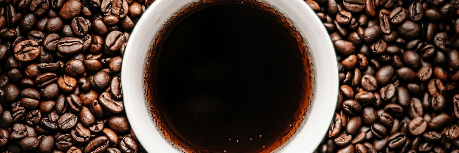 A mug of coffee sitting amidst the coffee beans