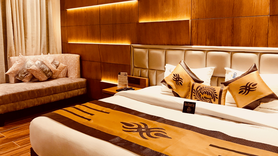 An Executive Room at JRD Pride - Business Hotel featuring a neatly-made bed, a sofa, wooden flooring, and modern ambient lighting.