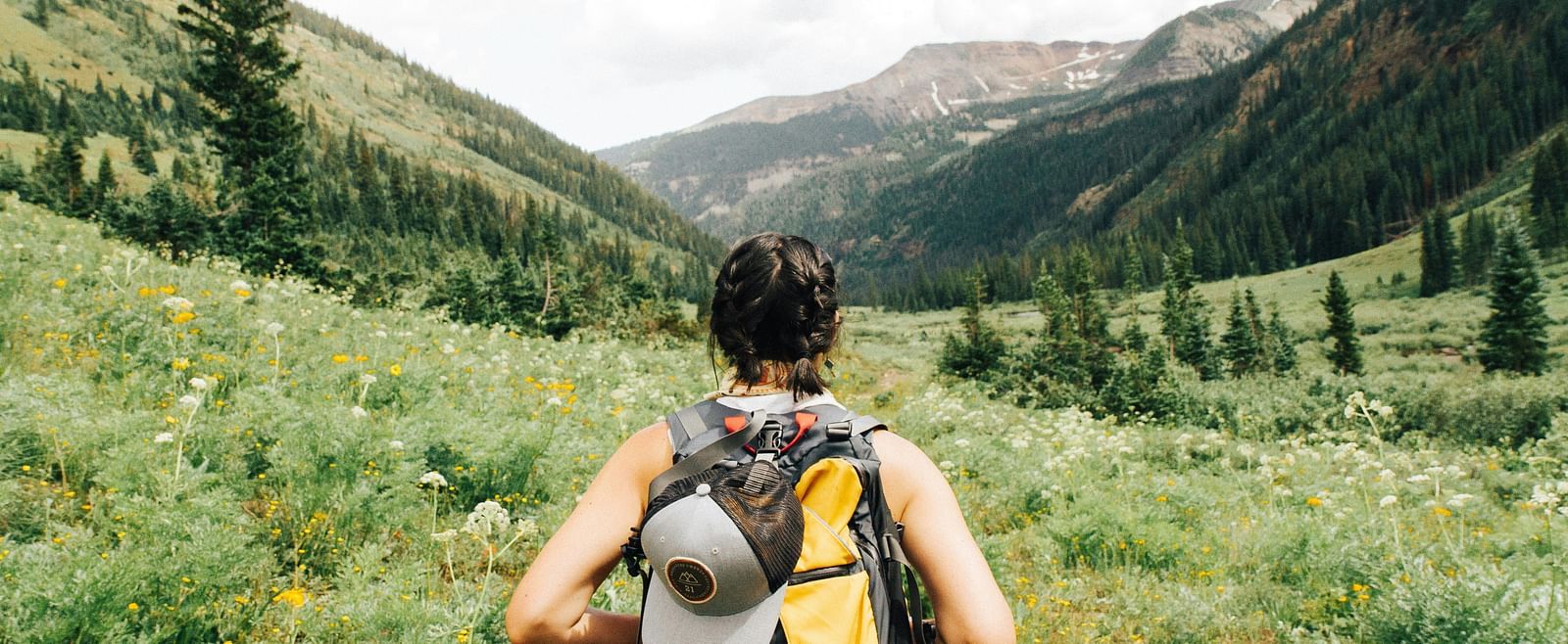 A woman backpacker standing in a lush green valley
