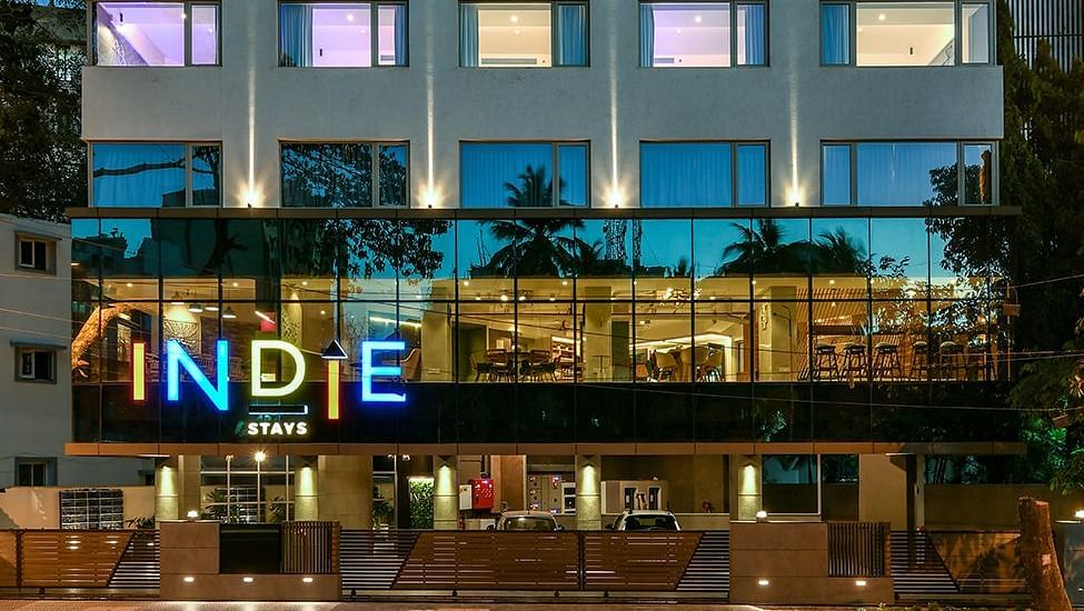 The facade of Indie Stays, BKC, shines against the night sky, with interior lights illuminating the building, creating a highlighted and inviting look