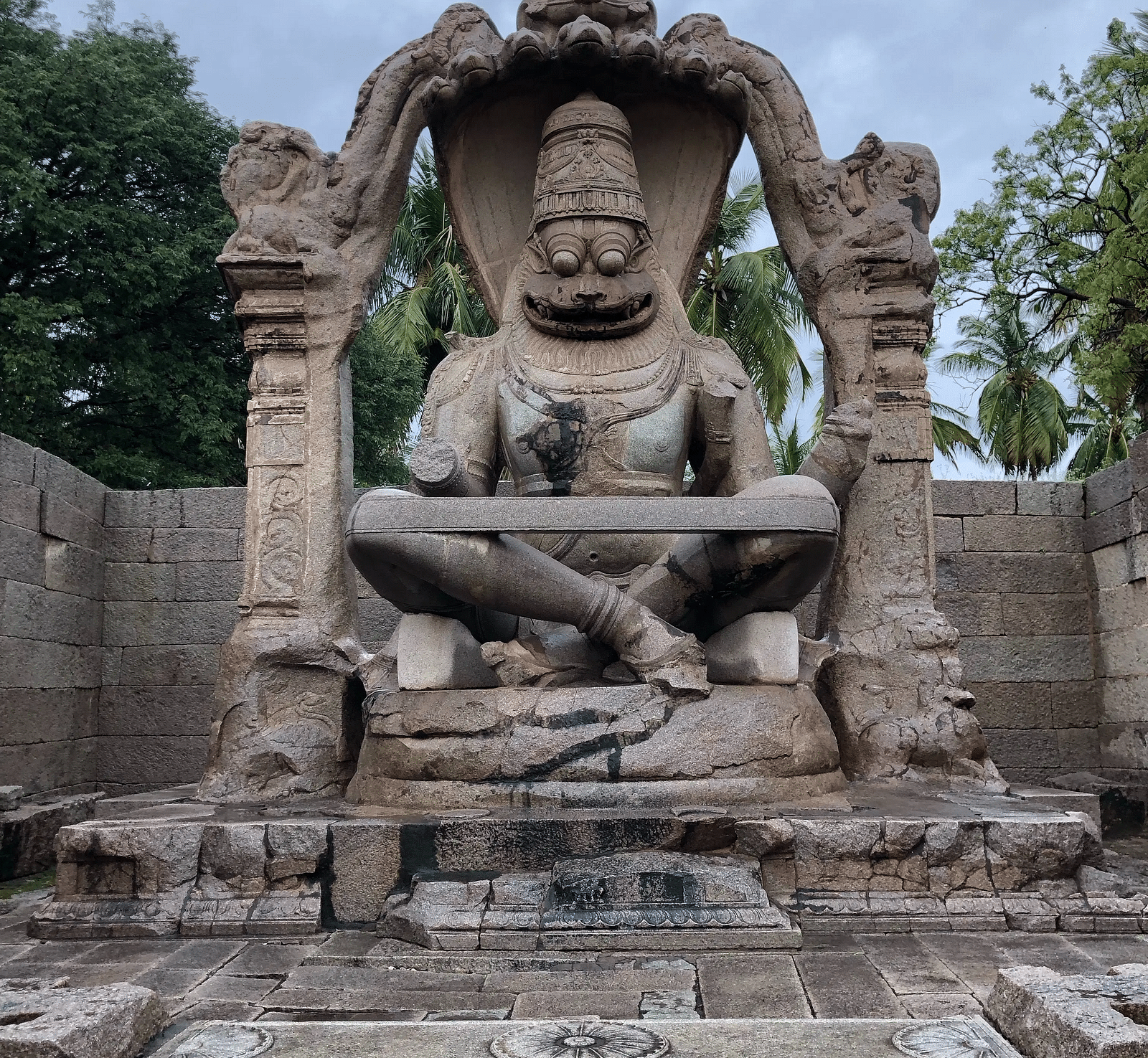 a huge stone statue kwpt on a pedestal with a cloudy sky in the background