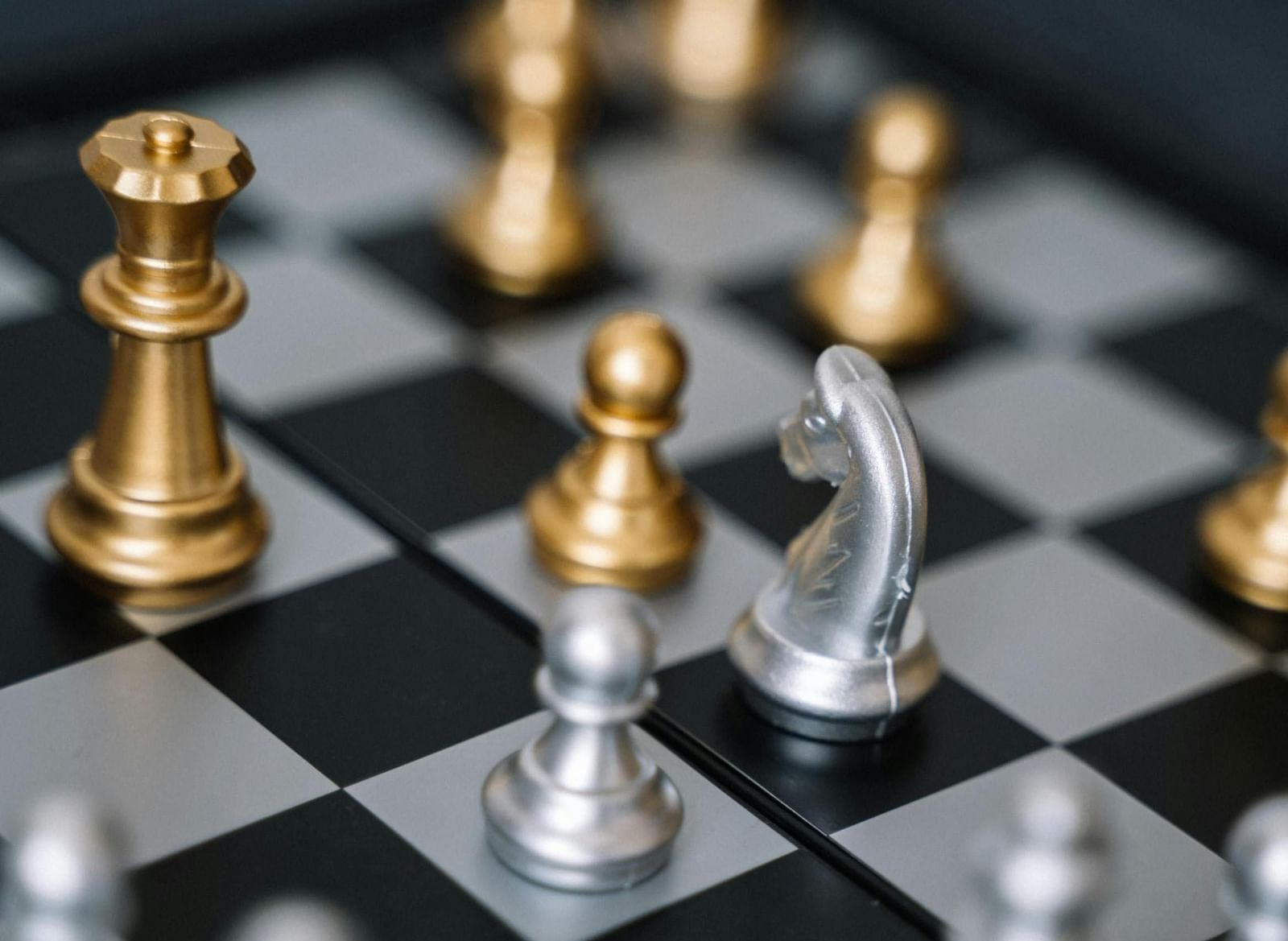 A chessboard with various gold and silver chess pieces.