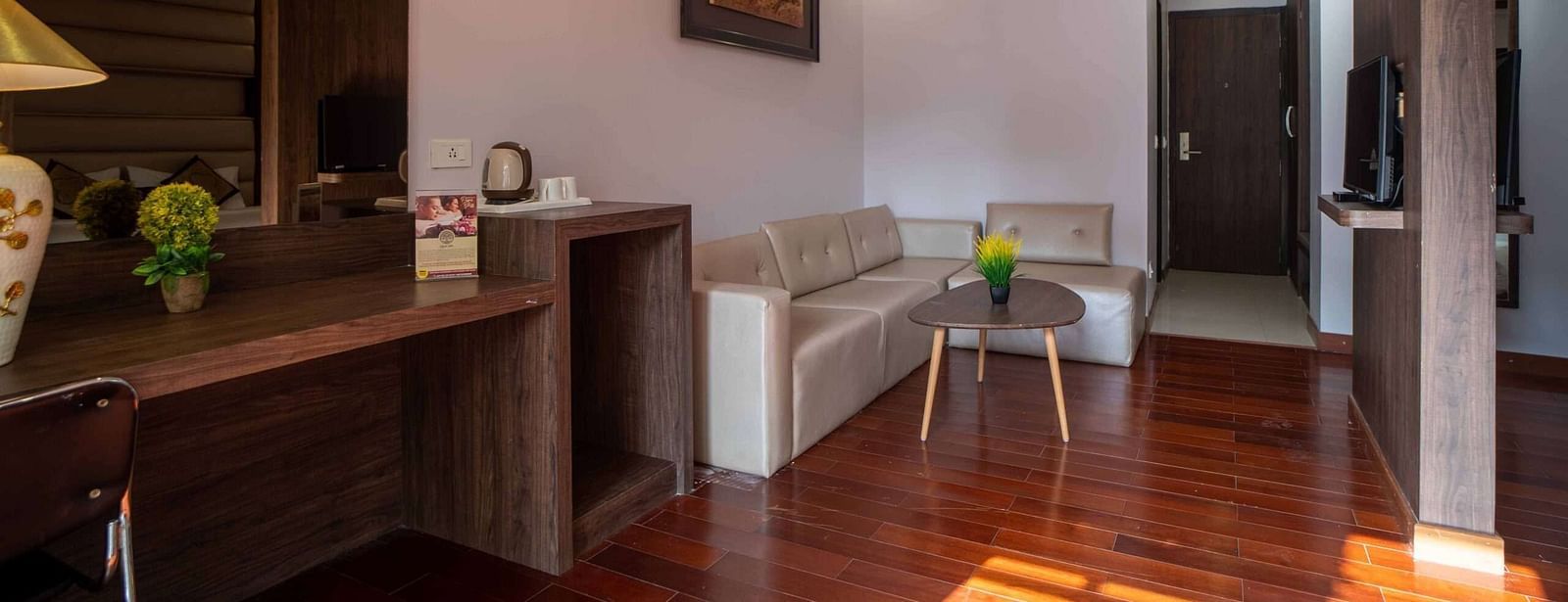 A hotel room at Mansha Hotel Regency with wooden flooring, a large bed, a work desk area, and a ceiling fan.