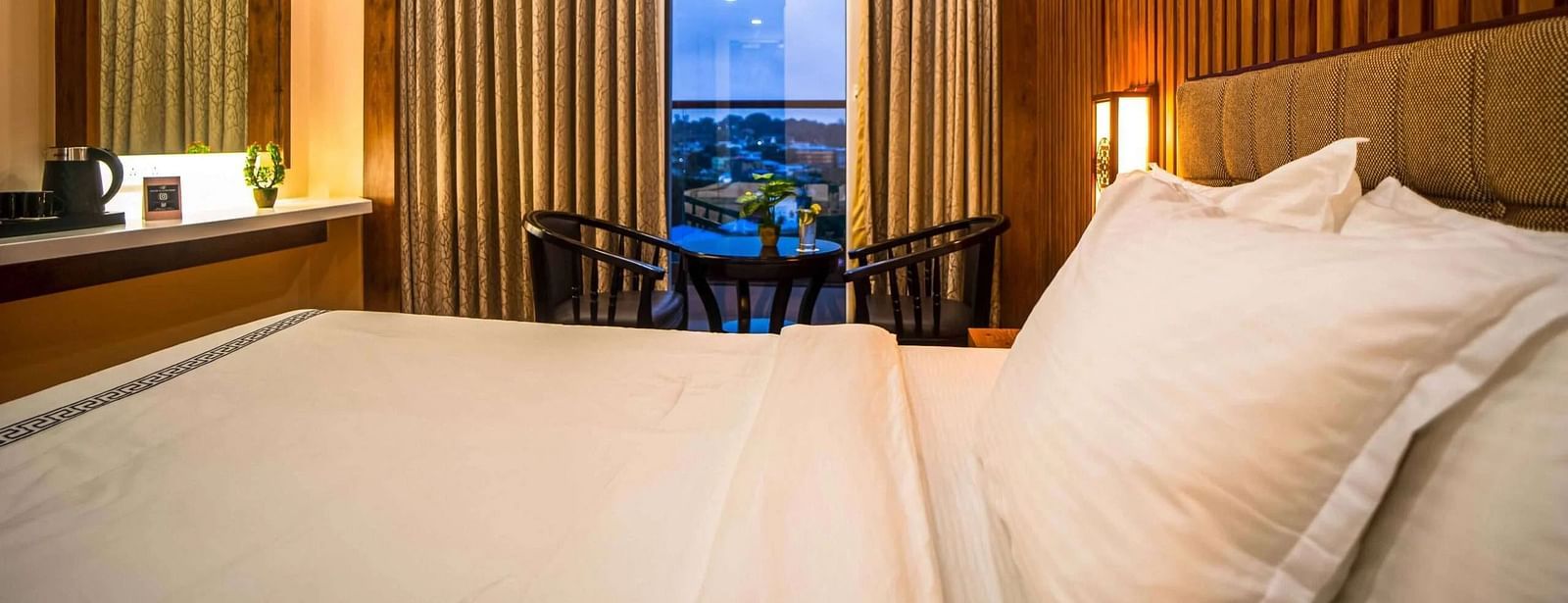 A comfortable bedroom at Mansha Palace features a cozy bed, wooden walls, and a small seating area by the window.