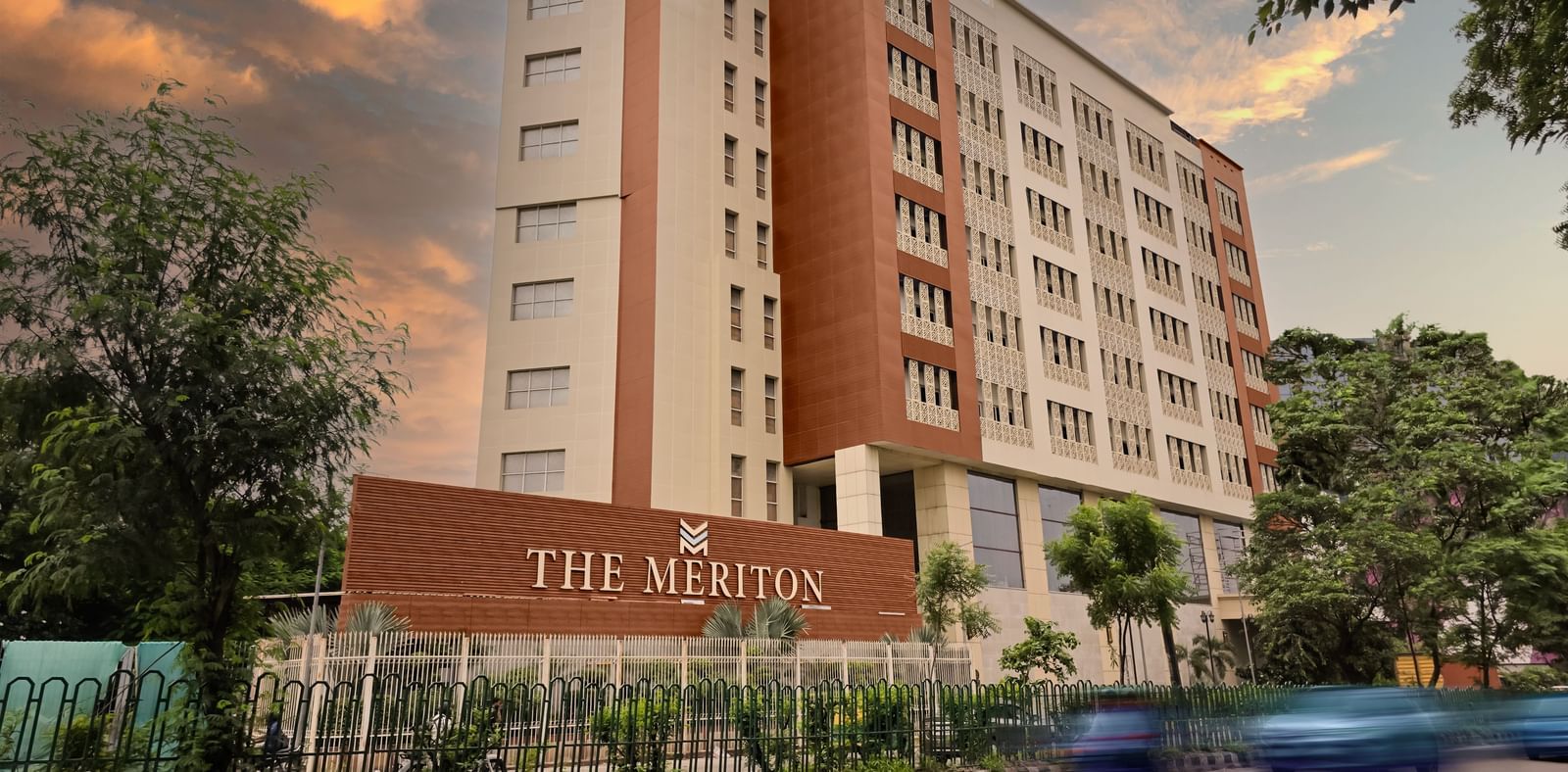 The exterior of The Meriton during the early evening with a road in front of it featuring a beautiful evening sky in the background.