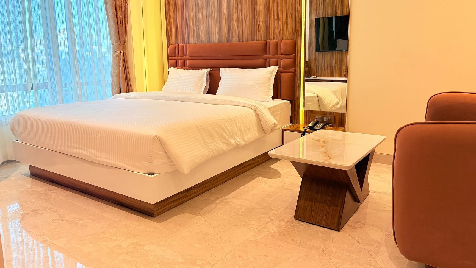 A bed with a wooden headboard and a television reflected in the mirror at Hotel Mumbai House, Vashi.