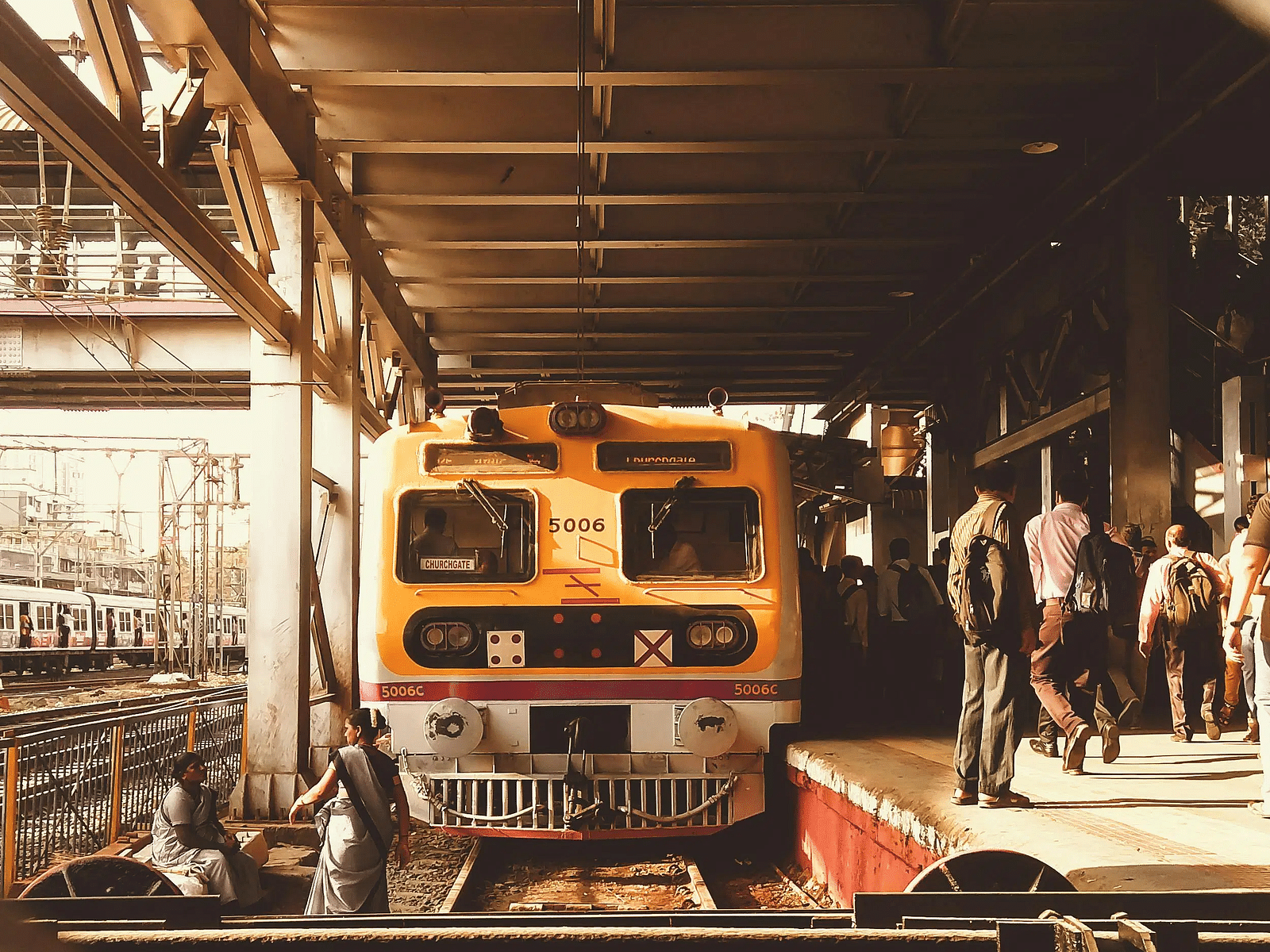 Local train at a crowded platform in an urban railway station, with passengers boarding and disembarking
