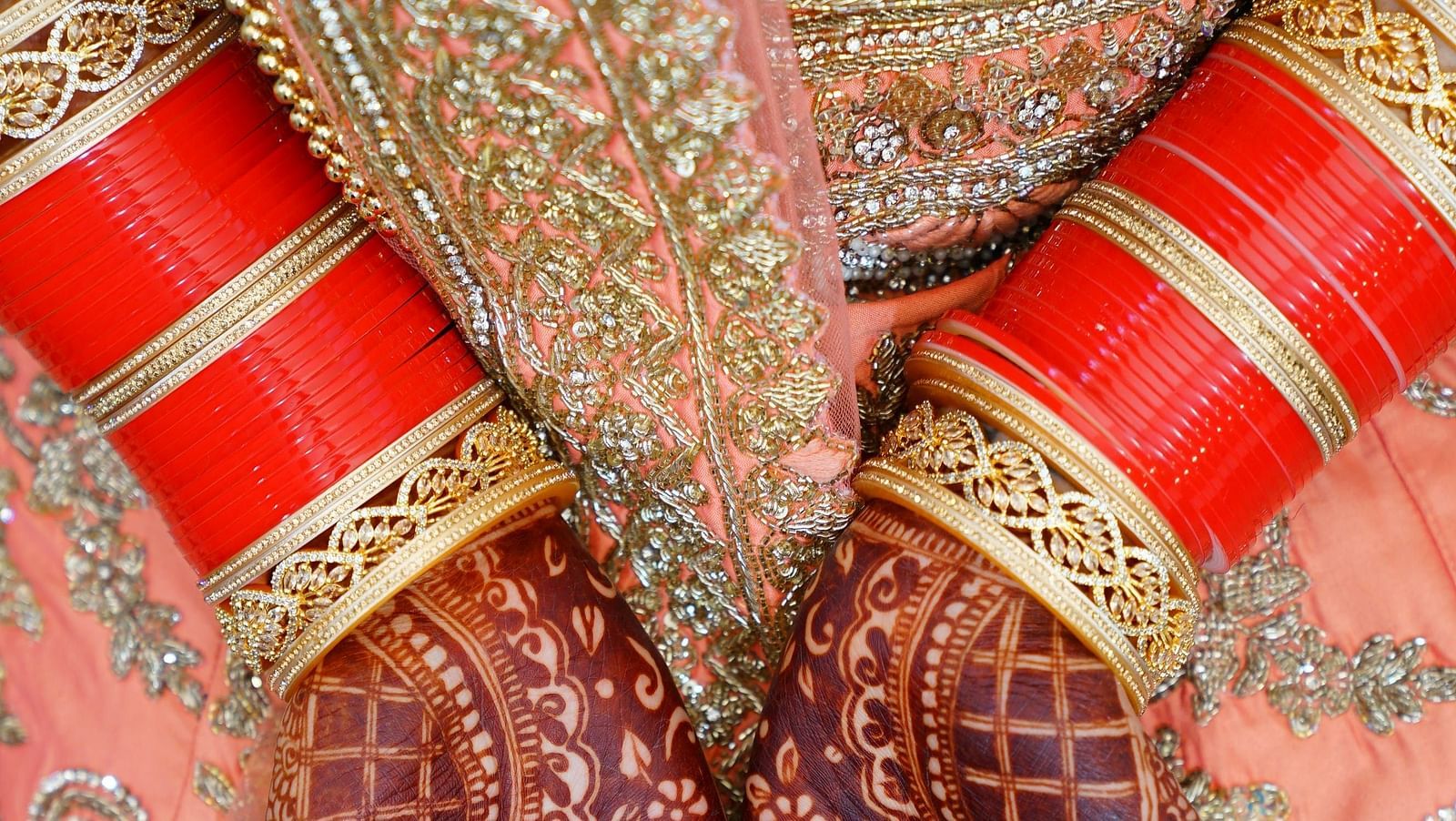 A close up shot of a henna stained hands with bangles