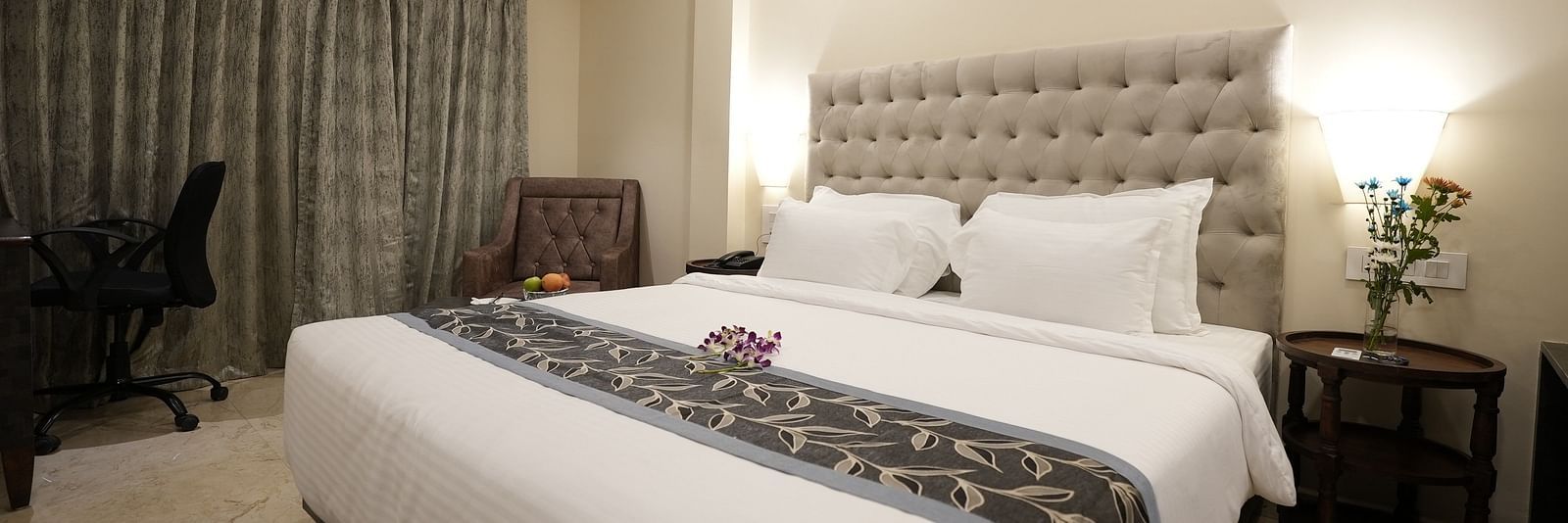 Modern hotel room with a work desk, large bed, and grey curtains at The Verda de Miranda Resort.