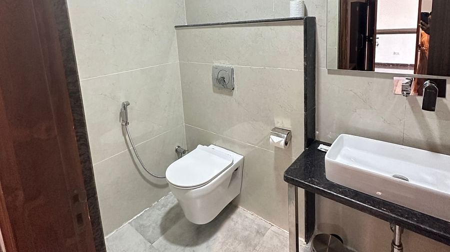 Bathroom includes a white toilet, a washbasin with a dark wooden cabinet, and light-coloured tiles - Kankidham Lords Inn