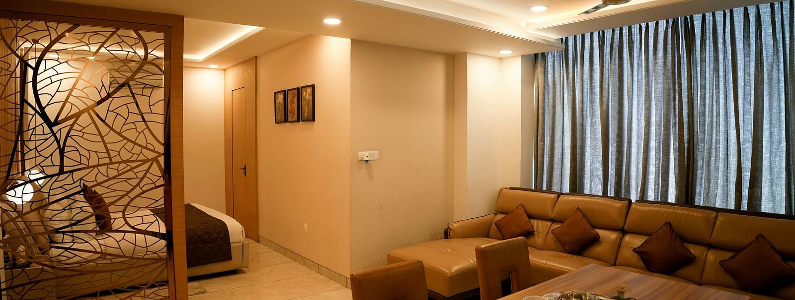 A spacious living room with a sectional sofa and decorative partition leading to another room - TGI Insignia, Bhopal