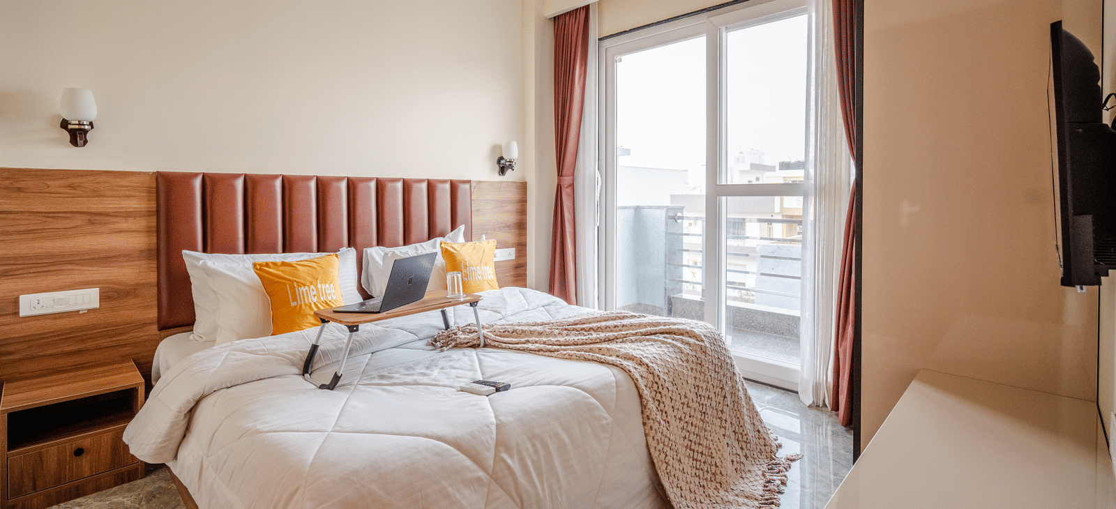 Comfortable bedroom with a large bed, soft furnishings, and a window view at Lime Tree 1BHK Service Apartment Near Artemis Hospital Gurgaon.