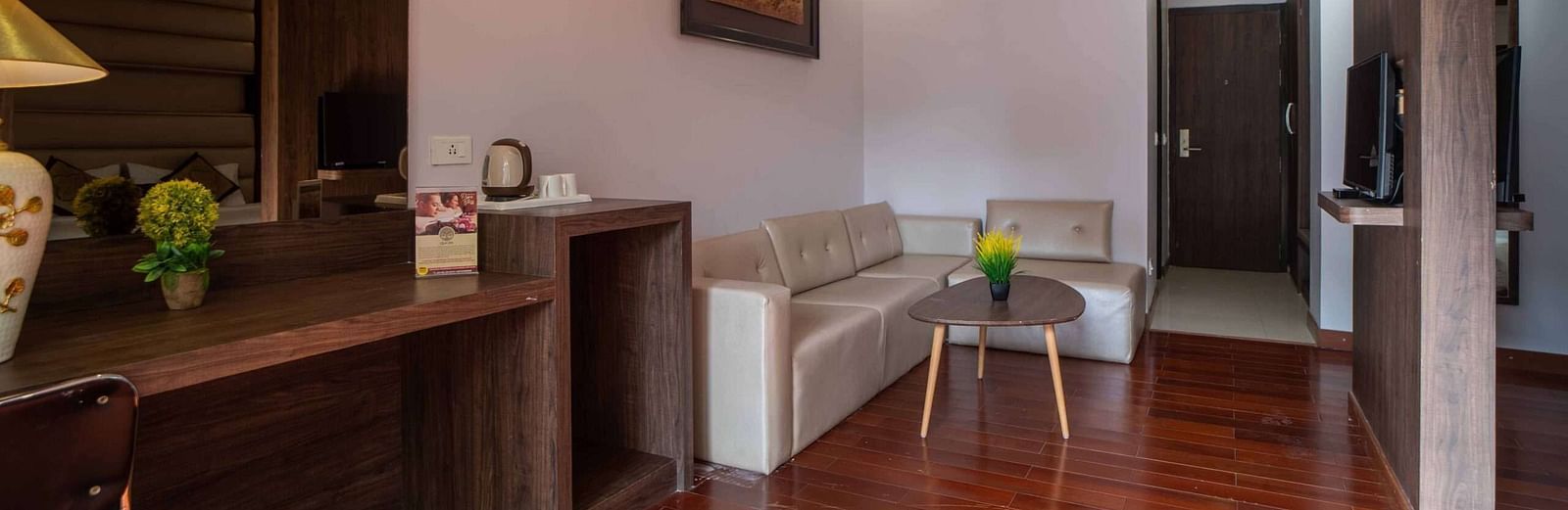 A hotel room at Mansha Hotel Regency with wooden flooring, a large bed, a work desk area, and a ceiling fan.