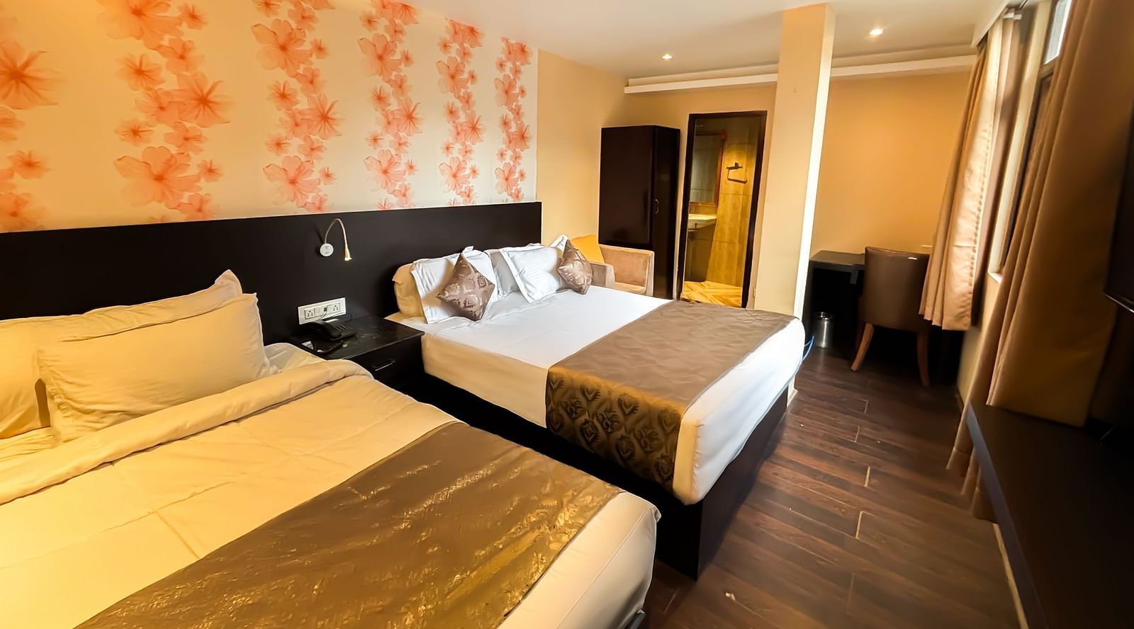 A bedroom with two queen size beds, a wardrobe, a table, and a chair at Avianna Hungry Jack, Gangtok.