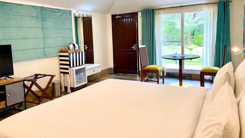A double bed with a tv opposite it inside Karma Cottages - Karma Lakelands.