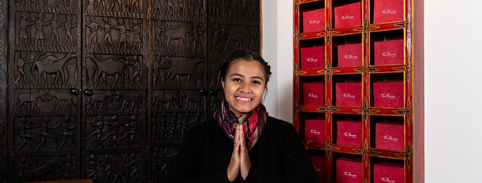 The reception desk at The Nanee where a woman is seen greeting warmly with folded hands