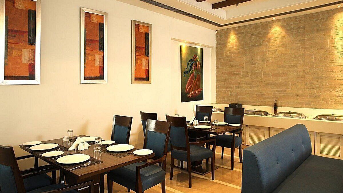 Tables and chairs neatly arranged with cutlery set on the table at Café Inde, Inde Signature Tower, Gurgaon